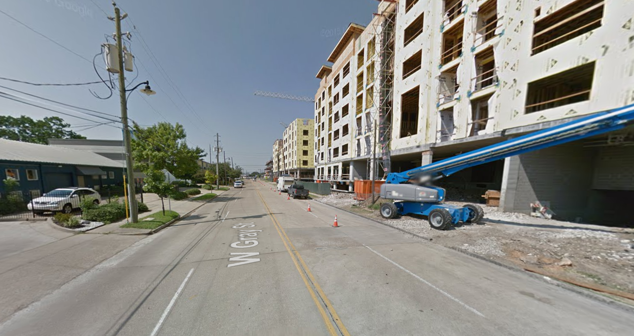 A four-lane road cutting through an urban neighborhood.