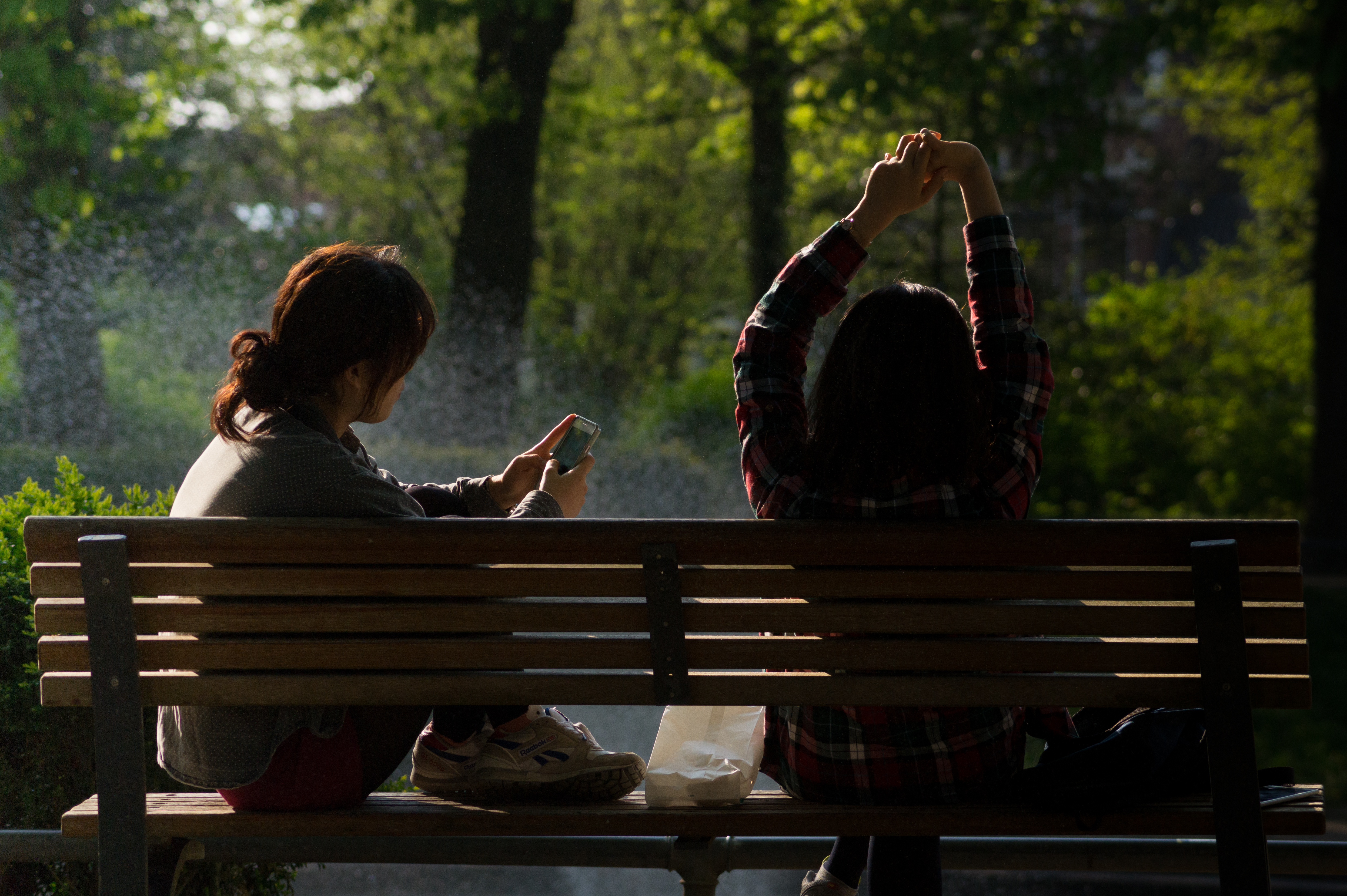 Woman sitting on a bench in a park using a smartphone